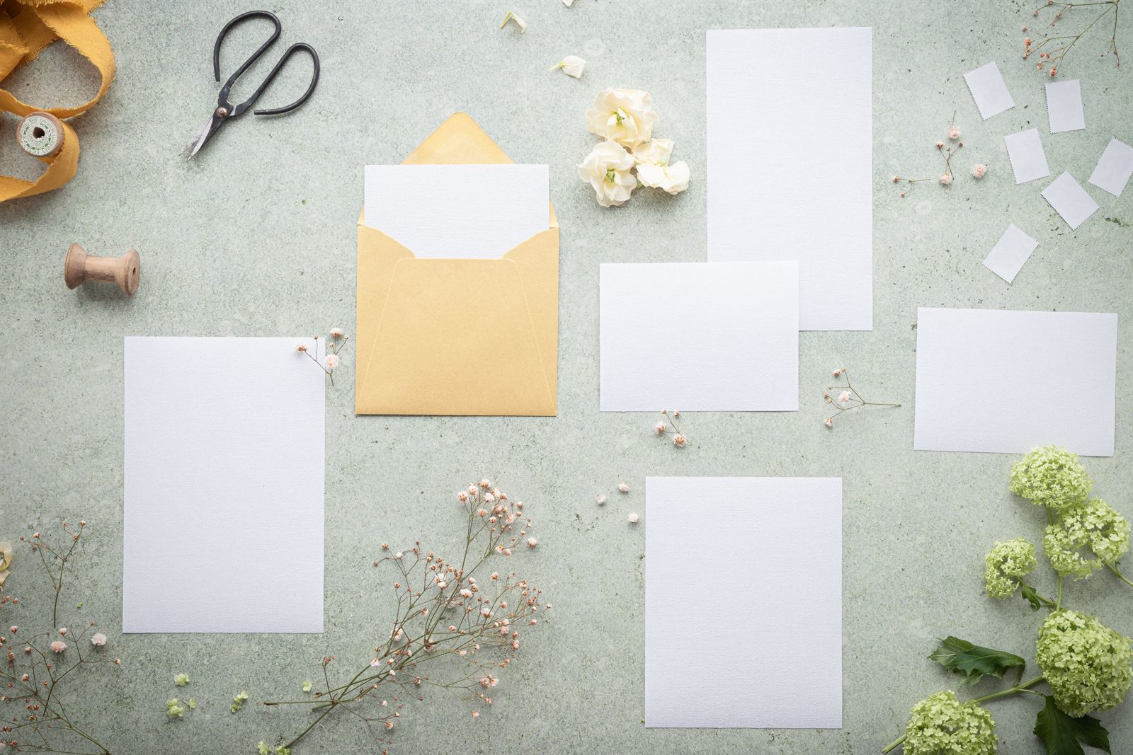 Blank cards and envelopes laid out with flowers and ribbon