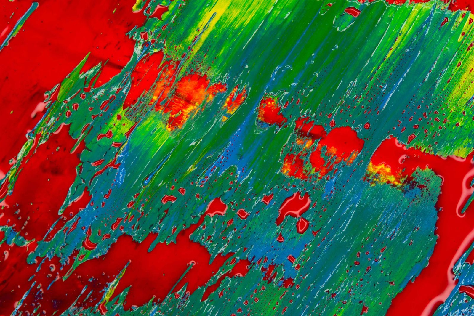 Green and blue squeegee strokes dragged across a deep red painted field